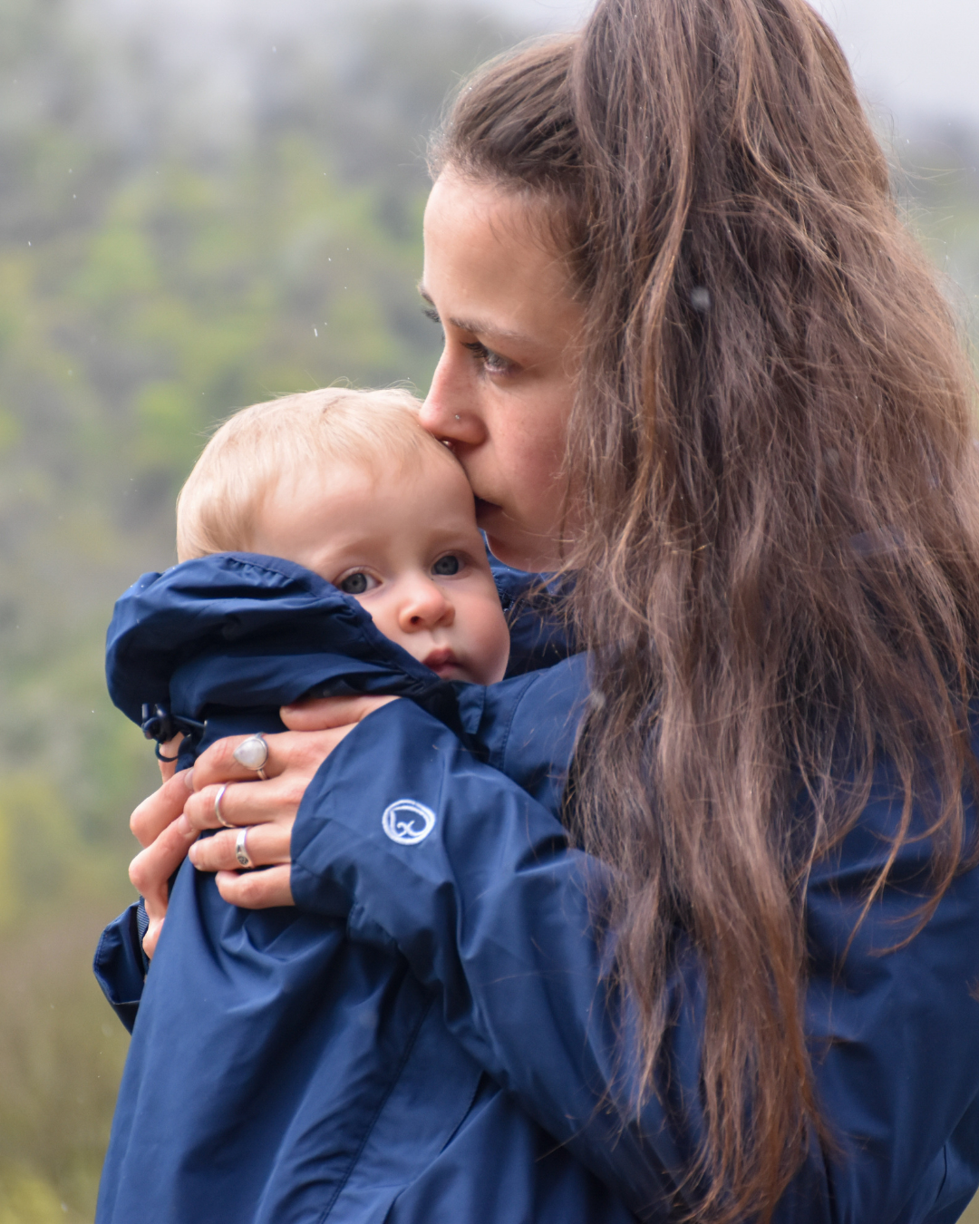Maman câline bébé en veste bleue, portrait rapproché, moment tendre en extérieur