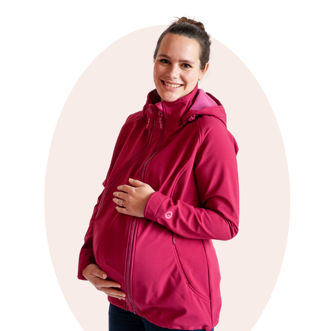 Femme enceinte en veste softshell rose tenant son ventre, prise de vue en studio