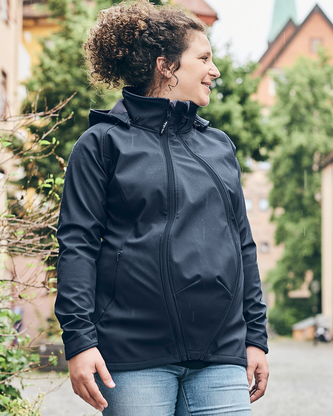 Femme enceinte en veste softshell noire dehors sous une légère pluie