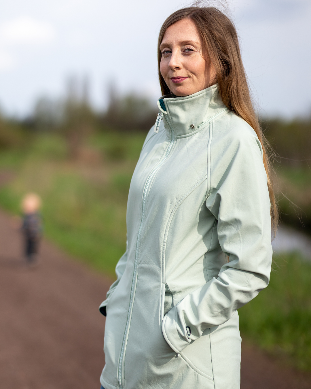 Femme portant veste softshell vert clair sur un chemin en pleine nature